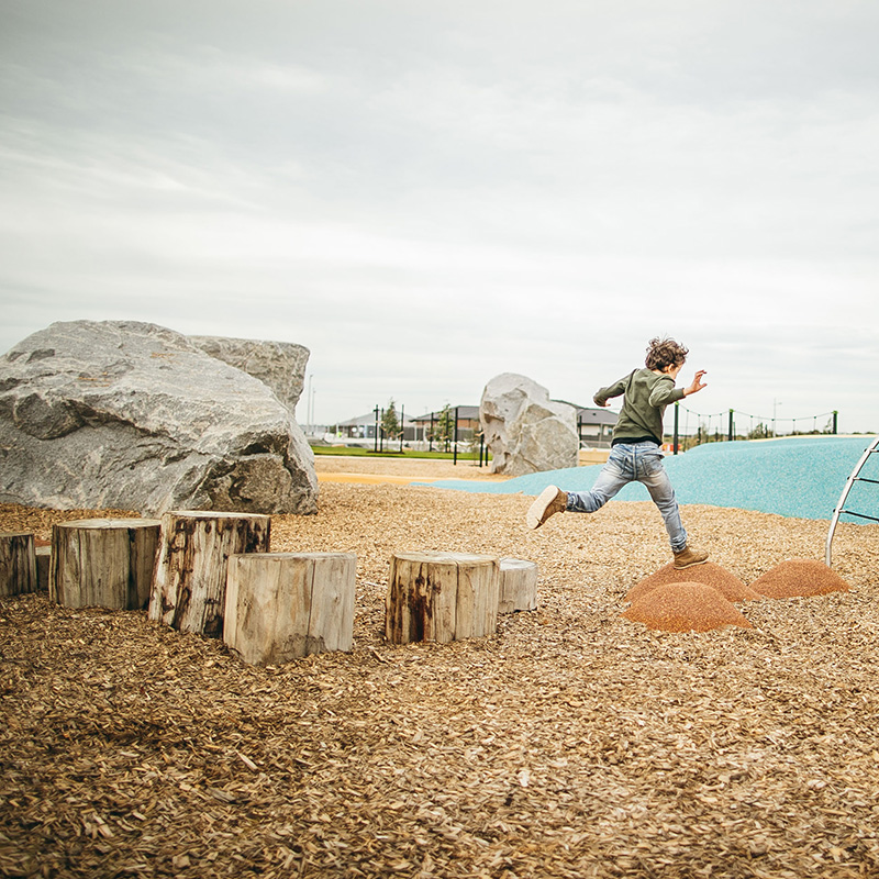Boy jumping on rocks at Raffles Park