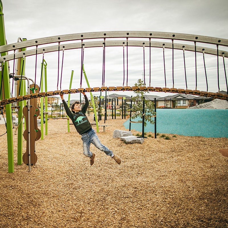 Boy swinging on bridge at Raffles Park
