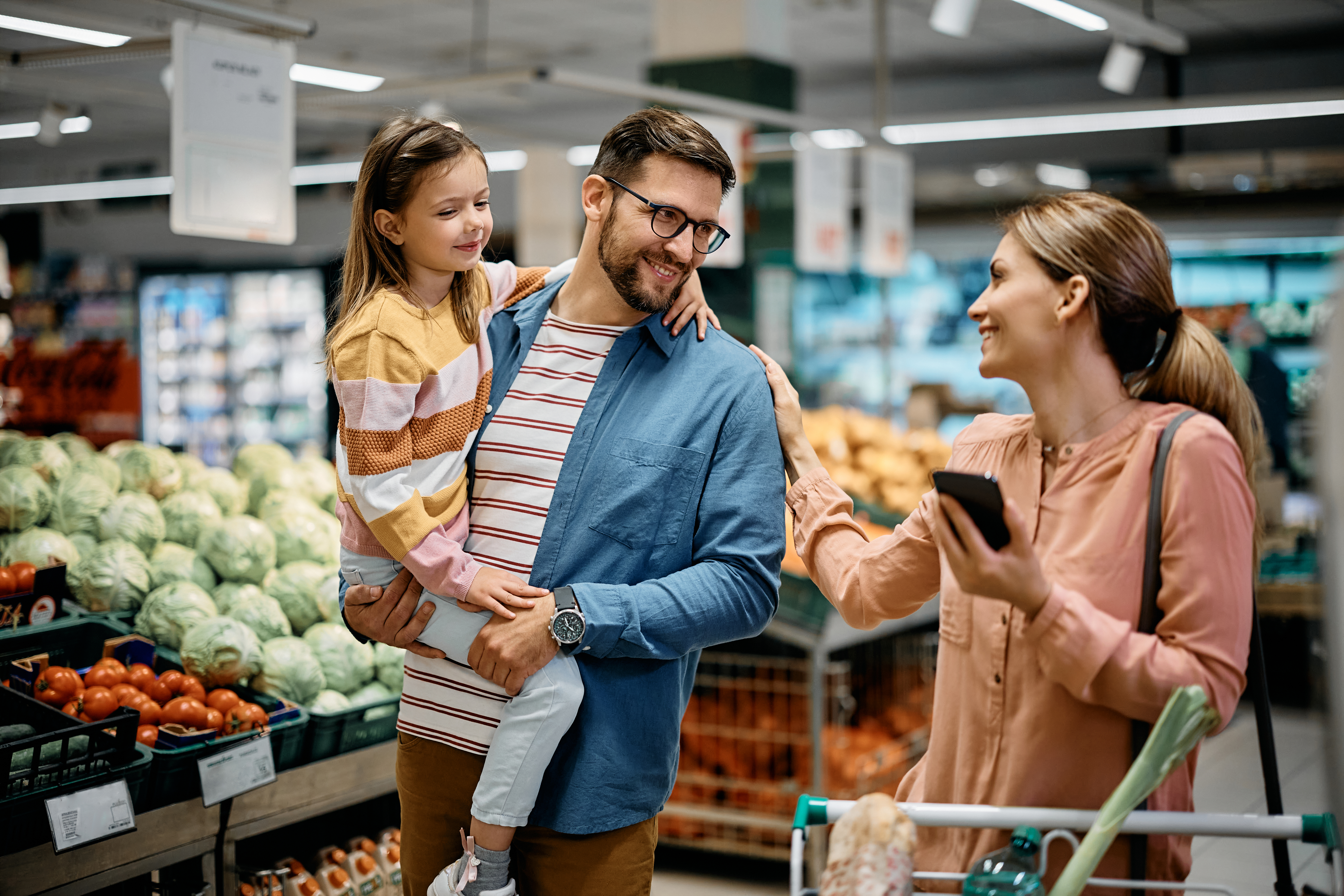Happy family talking while shopping together in supermarket.
