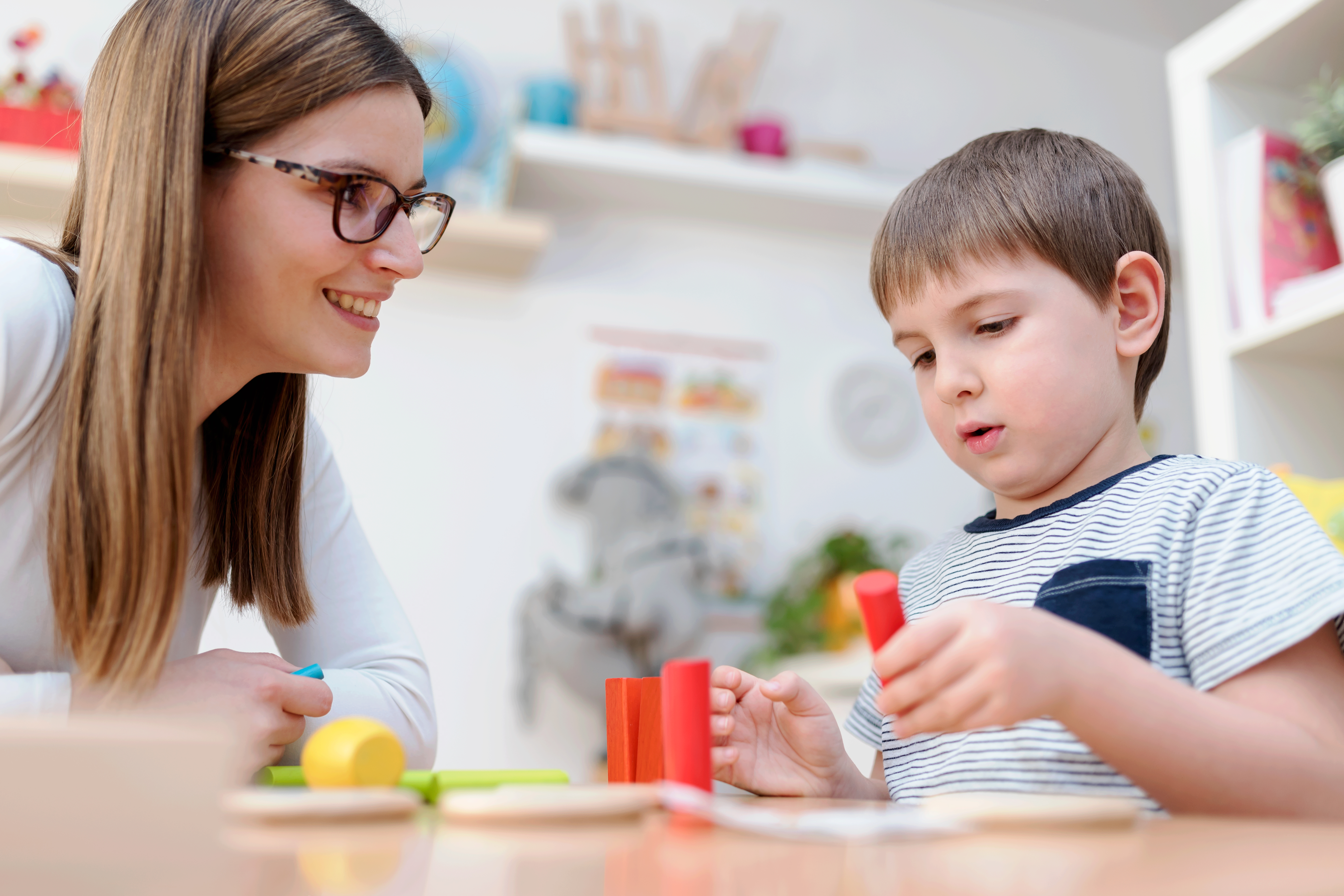 Proud mother looking at her son playing didactic games learning